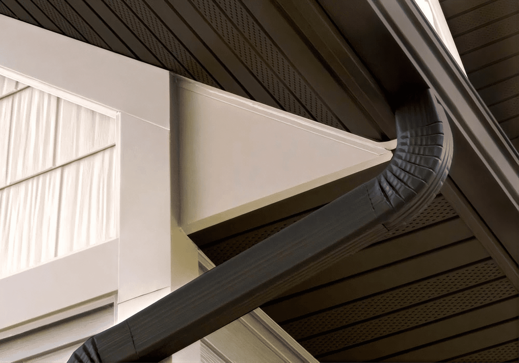 Retracted motorized awning with dark mesh fabric against cream exterior wall and soffit