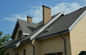 A brick house with with gray asphalt shingles and a gutter system