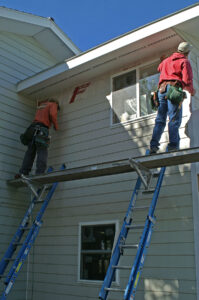 Workers on a scaffolding installing siding