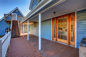 A home exterior features blue siding and wraparound porch