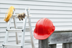 Red hardhat with ladder and house siding in the background